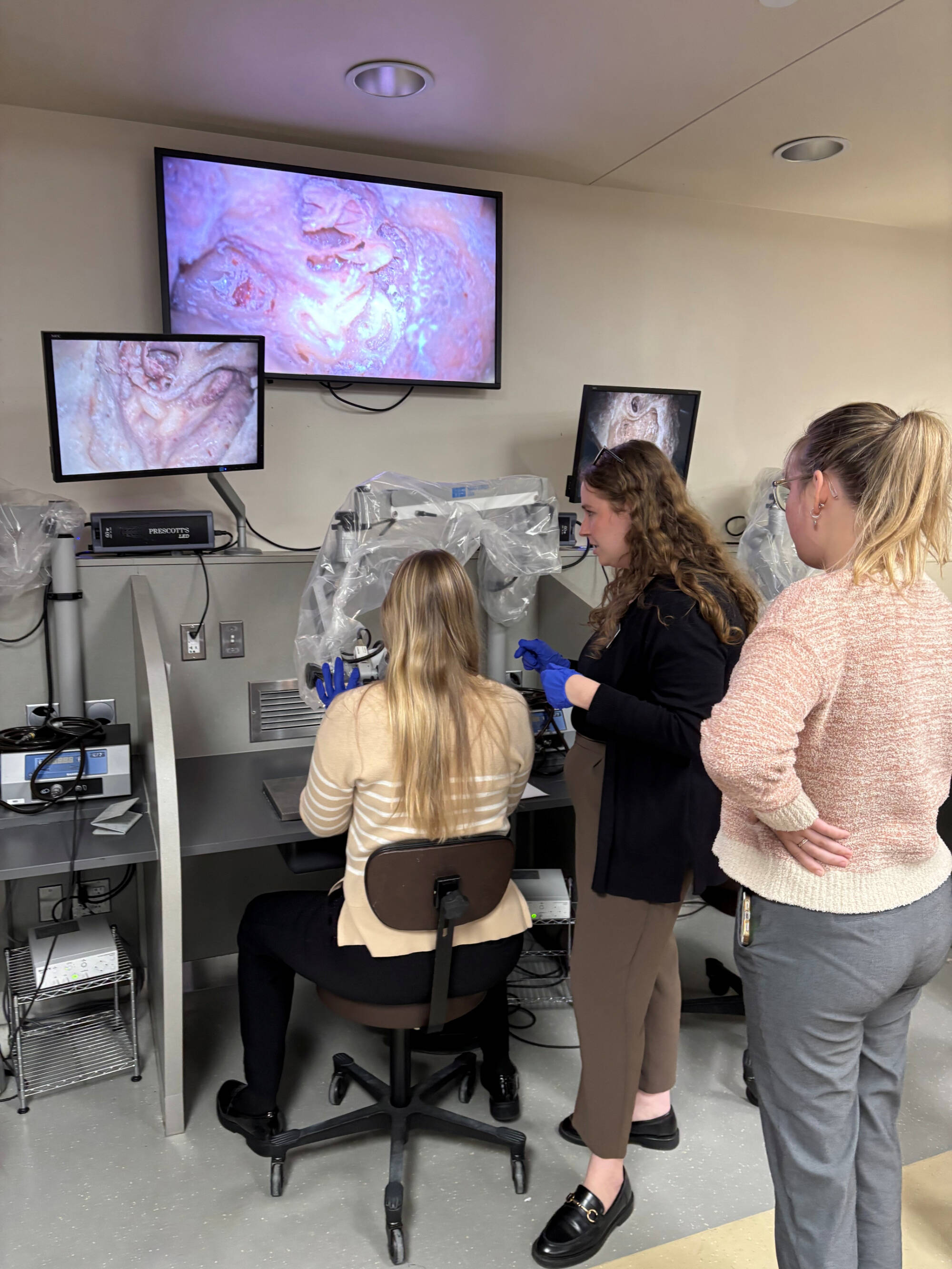 Three students surrounding audiology equipment